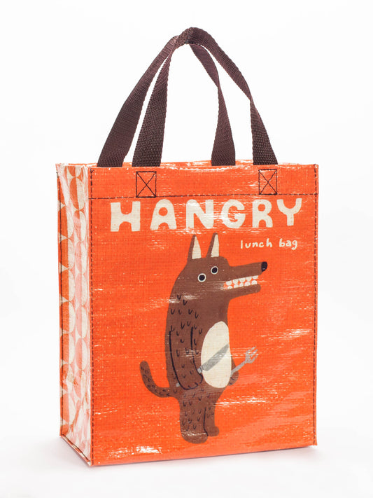 The Blue Q Hangry Handy Tote is an orange lunch bag with brown handles, featuring a cartoon wolf baring its teeth and holding a fork, plus the text "HANGRY lunch bag" on the front. Perfect for carrying your lunch in style!.