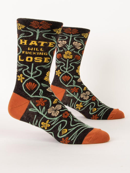 Blue Q Hate Will Fucking Lose M-Crew Socks: black combed cotton crew socks with orange toes and heels, bright floral patterns, and bold "HATE WILL FUCKING LOSE" text—wear these to spread love and positivity.