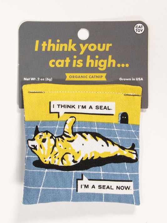 Blue Q’s I Think Your Cat Is High Catnip Toy comes in a package with a cartoon cat thinking it’s a seal. Contains organic catnip in a cotton pouch, grown in the USA. Packaging reads, “I think your cat is high…”.