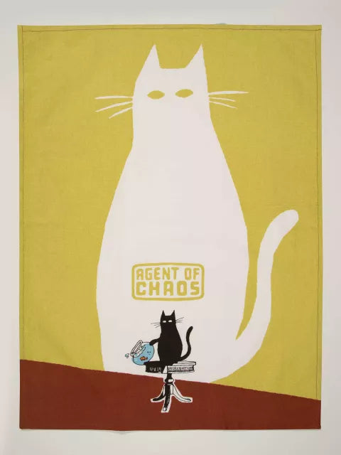 The Blue Q Agent of Chaos Dish Towel features a bold white cat with glowing eyes and "Agent of Chaos" text, plus a sassy black cat beside a spilled cup and the words, "Keep it interesting. Love you for your mischief!.