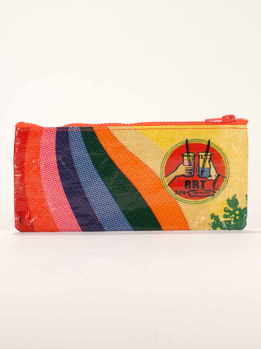 The Blue Q Art Supplies Pencil Case features diagonal rainbow stripes and a circular logo with two paintbrushes in jars labeled ART SUPPLIES on the right side.