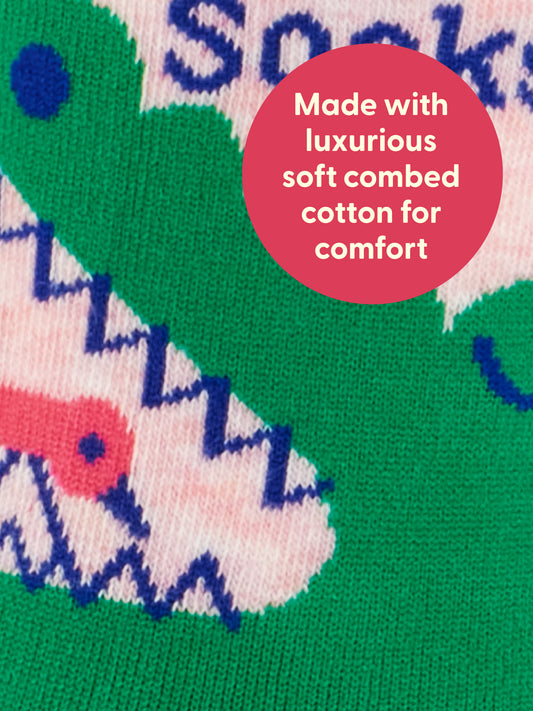 Close-up of colorful patterned fabric, primarily green with pink, blue, and white details. A red circle contains white text: Quiet Time Socks. We Don’t Talk Now. W-Crew Socks by Blue Q—crafted from luxurious soft combed cotton for comfort. Perfect for anyone who wants stylish socks that feel as good as they look.