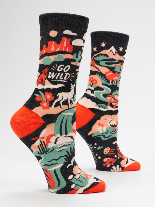 Step into adventure with the Blue Q Go Wild W-Crew Socks, featuring vibrant wilderness-inspired designs of mountains, trees, and animals. One sock displays the playful phrase “GO WILD,” while bright orange toes and heels add a bold pop. Crafted from soft combed cotton for all-day comfort, these women’s shoe socks are a colorful must-have for any explorer.