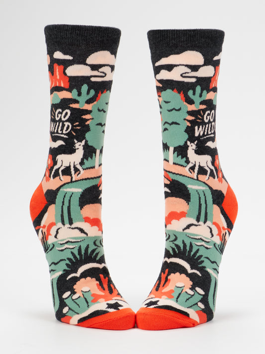 Blue Q’s Go Wild W-Crew Socks are made from soft combed cotton for extra comfort and feature a vibrant, multicolored wilderness scene with trees, mountains, a deer, and the phrase “GO WILD” against a white background. These women’s shoe socks have striking red toes and bring color to your outfit with their bold nature-inspired design.