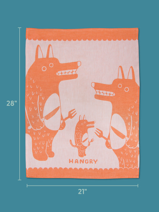 The Blue Q Hangry Dish Towel is a 28 x 21-inch orange and white towel featuring cartoon wolves with utensils and the word "HANGRY" underneath, shown on a blue background.