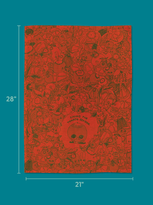Celebrate your love of fresh tomatoes with the Blue Q Living For Tomato Season Dish Towel, featuring red fabric adorned with black line art of assorted vegetables and whimsical characters. The center showcases the phrase “Living For Tomato Season.” Measuring 28 by 21 inches, this vibrant towel is perfect for any tomato enthusiast and is displayed on a teal background.