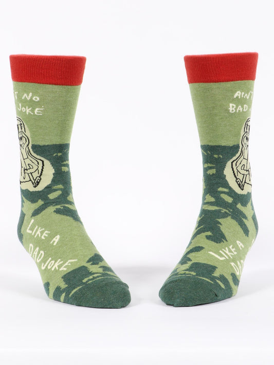 Blue Q's Ain't No Bad Joke Like A Dad Joke M-Crew Socks are green novelty socks with red tops, fun illustrations, and the phrase “Ain’t No Bad Joke Like a Dad Joke” in white.