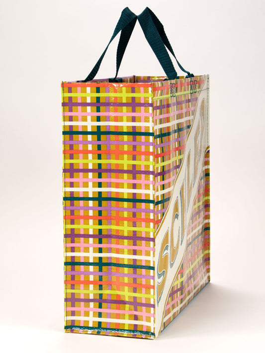 The Schlep Shopper by Blue Q is a rectangular bag with green handles and a vibrant yellow, pink, red, and white plaid pattern. The side features bold “SCI...” lettering—a stylish essential for carrying it all.