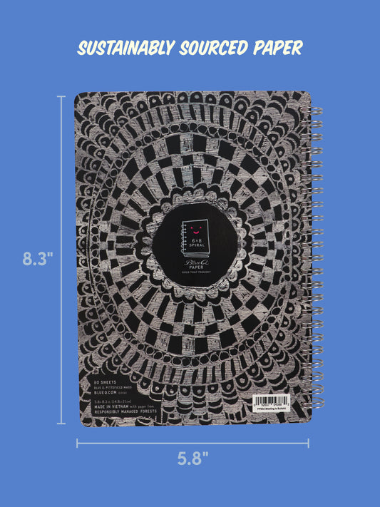 A Blue Q “This Meeting Is Bullshit” 6x8 spiral notebook with a bold geometric black and white cover, perfect for jotting down observations and statements. Displayed on a blue background with the text “Sustainably sourced paper” above.