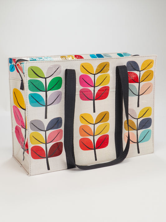 The Blue Q Sprout Shoulder Tote features black handles and colorful, stylized leaf patterns on white—perfect for shopping in style.