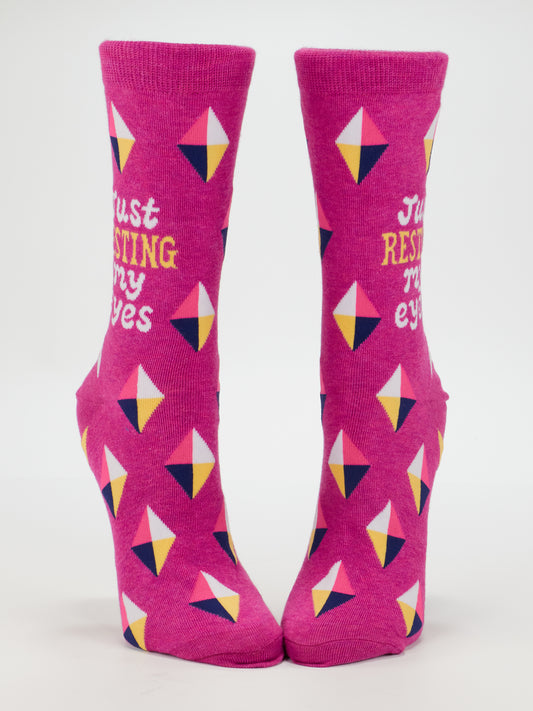 Blue Q’s Resting My Eyes W-Crew Socks feature bright pink geometric diamond patterns in yellow, white, navy, and pink. Made from soft combed cotton for women’s sizes 5–10 with “Just RESTING my eyes” embroidered on the front.