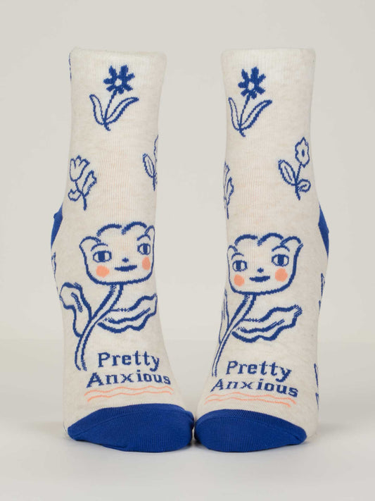 Blue Q's Pretty Anxious W-Ankle Socks fit women's shoe sizes 5-10. These white combed cotton socks feature blue toes and heels, cheerful pink-cheeked flowers, and “Pretty Anxious” on the sole.